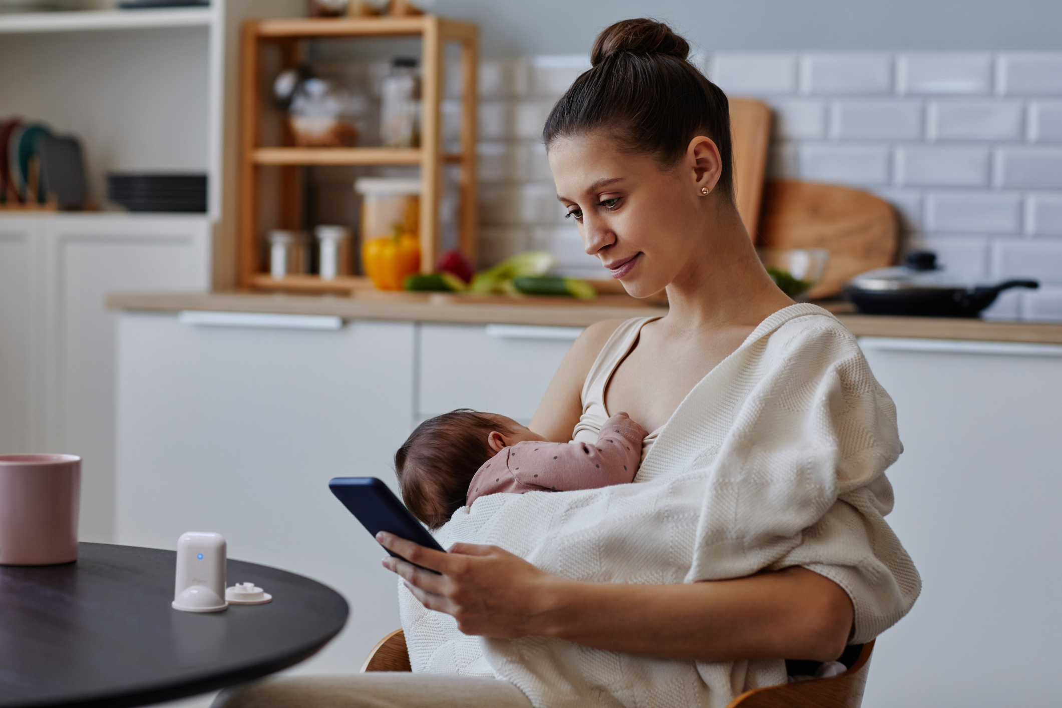 mother using the mylee milk / colostrum sensing device and looking at the MyLee App to get breastfeeding and milk supply insights